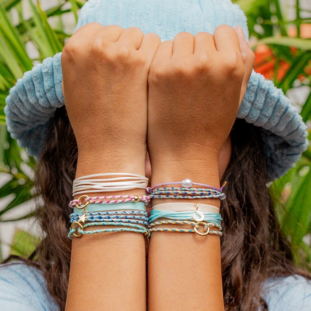 Two people wearing colorful bracelets with a blurred natural background